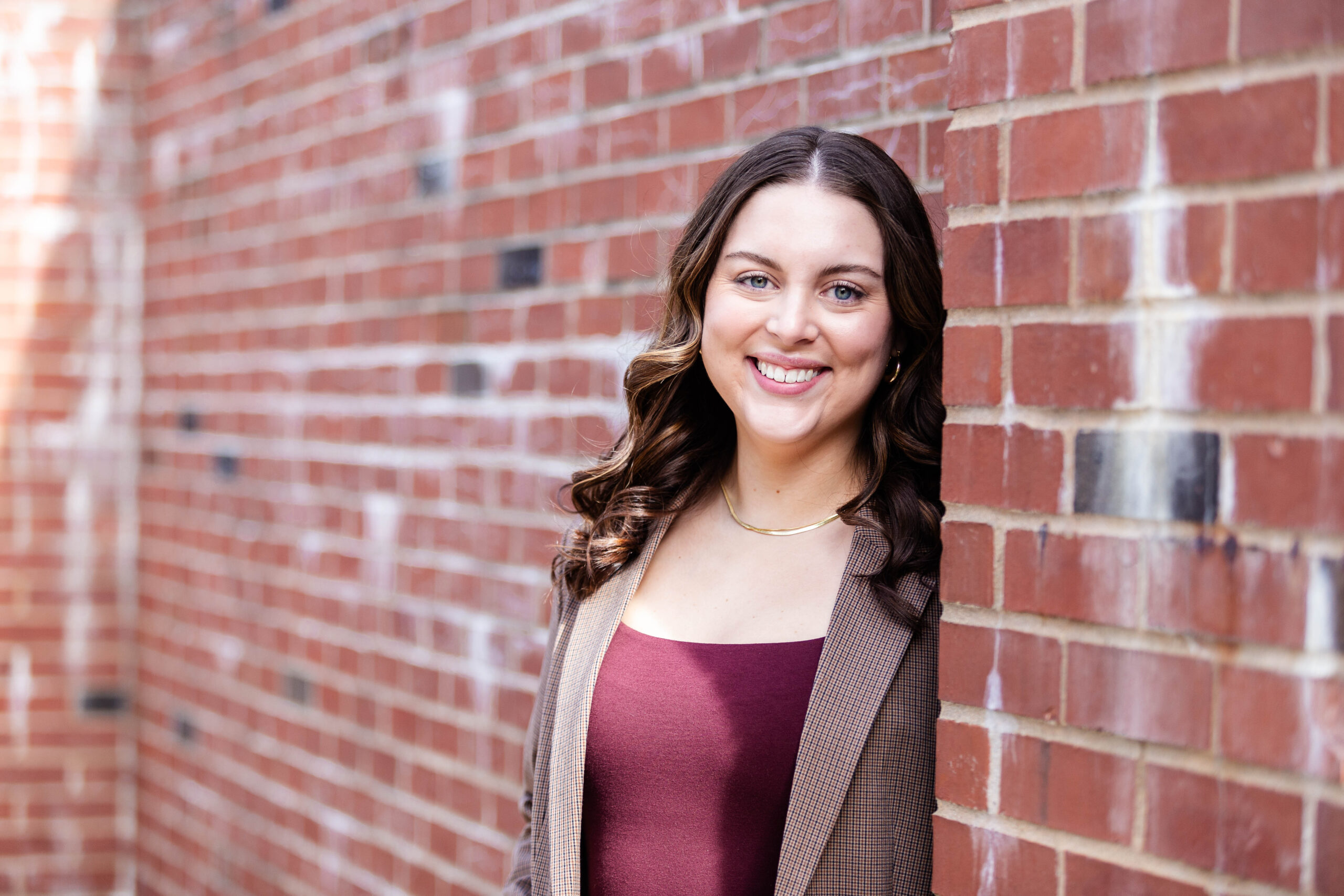 Dakota Richmond, a female student with brown hair, leans up against a brick wall