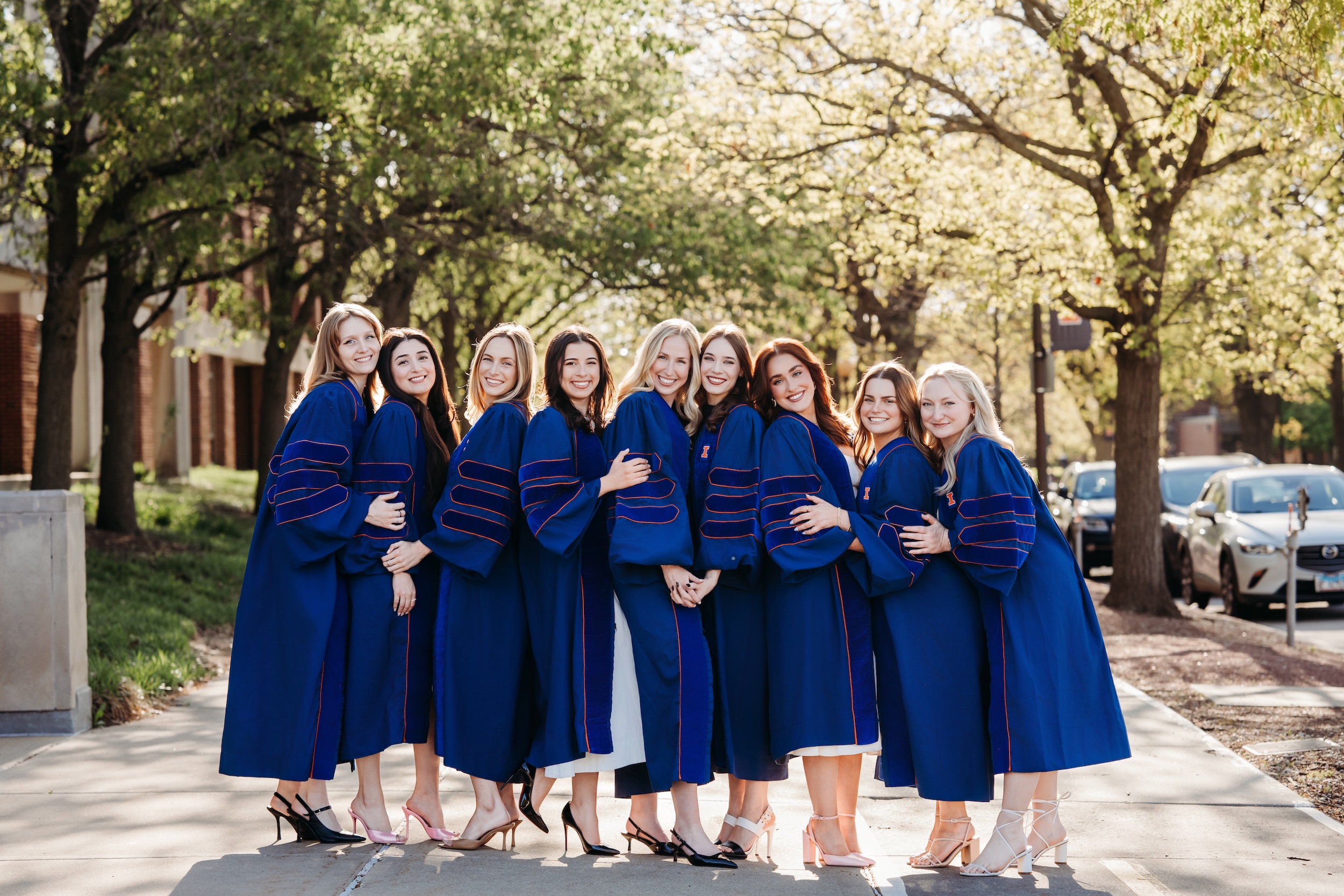 A group of female 2025 graduates poses for a photo outside of the Law building