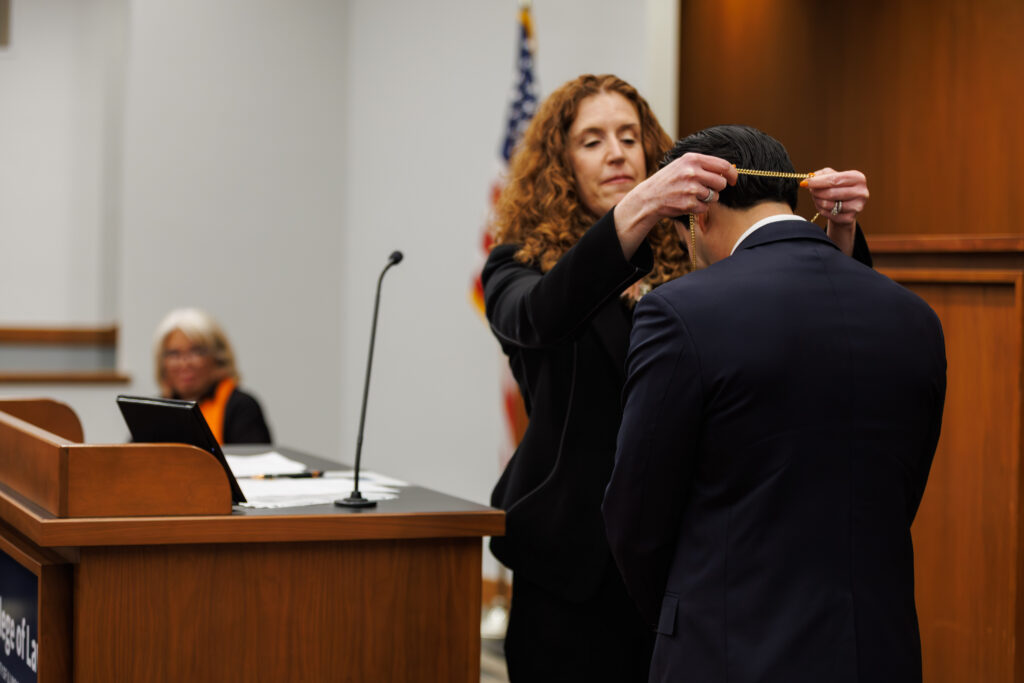 Professor Colleen Murphy places a medallion around the neck of Professor Jake Sherkow during his investiture ceremony.