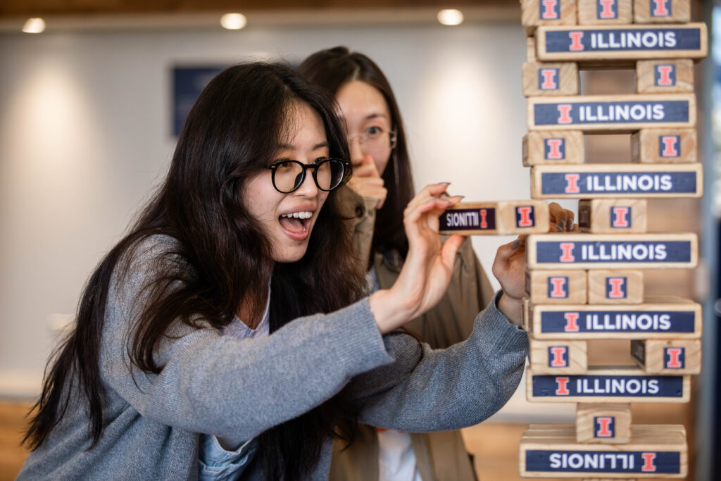 Two Asian women play a block-stacking game during new student orientation for international students.